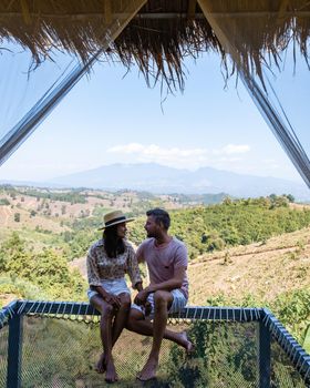 couple man and woman on vacation in Nan Thailand drinking coffee and high tea with a look over the countryside of Nan Thailand. Asia