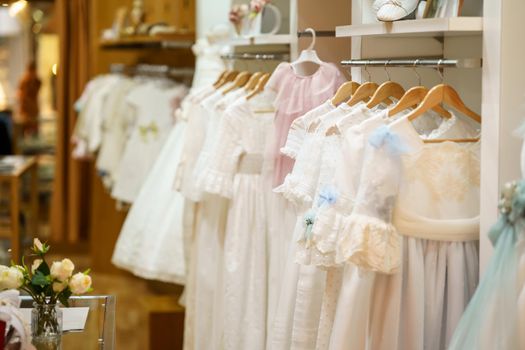 Display rack with first communion dresses for girls in a luxury children's clothing shop. Children's party dresses shop.