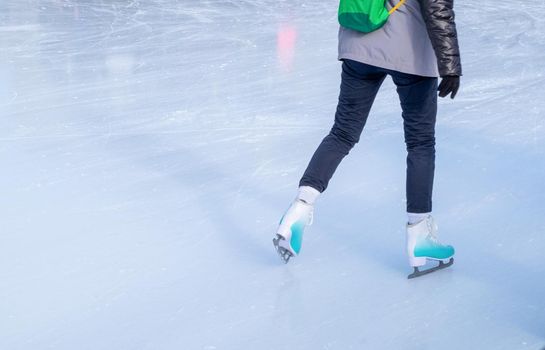 A young girl skating in winter clothes for outdoor activities at the rink in winter. Healthy lifestyle, active rest. Horizontal orientation, selective focus.