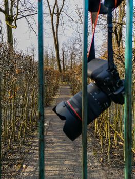 Camera hanging on strap behind old metal fence in labyrinth in park