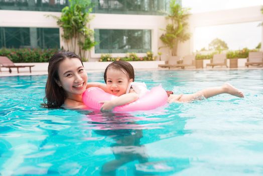 Mother and baby girl having fun in the pool. Summer holidays and vacation concept