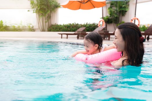 Mother and baby girl having fun in the pool. Summer holidays and vacation concept