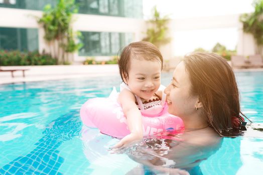 Mother and baby girl having fun in the pool. Summer holidays and vacation concept