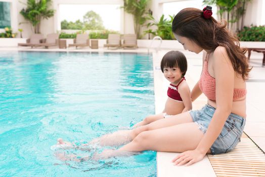 Mother and baby girl having fun in the pool. Summer holidays and vacation concept