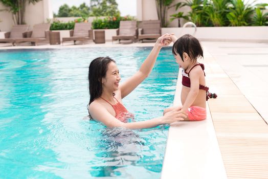 Mother and baby girl having fun in the pool. Summer holidays and vacation concept