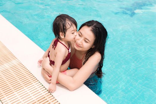 Mother and daughter having fun in the pool. Summer holidays and vacation concept