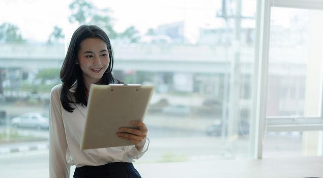 Banner wide image, Happy Asian young businesswoman reading Company information, report income in the bright workplace.