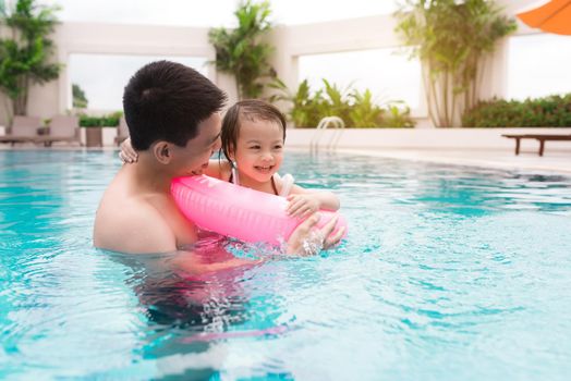 Father and daughter having fun in the pool. Summer holidays and vacation concept