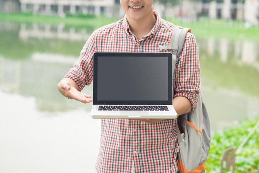 Male asian hand showing laptop screen outdoors