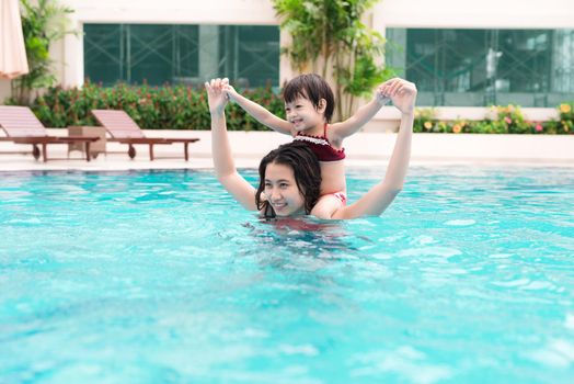 Mother and baby girl having fun in the pool. Summer holidays and vacation concept