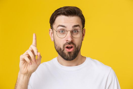 Young man looking at copyspace having a surprised or satisfied look isolated on yellow background