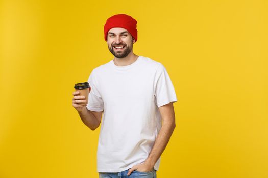 Man on isolated vibrant yellow color taking a coffee in takeaway paper cup and smiling because he will start the day well