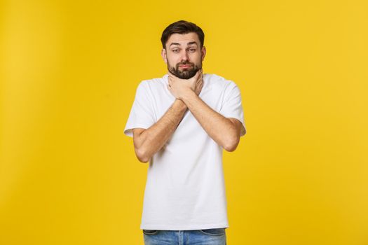 Worried young man standing isolate on yellow wall.