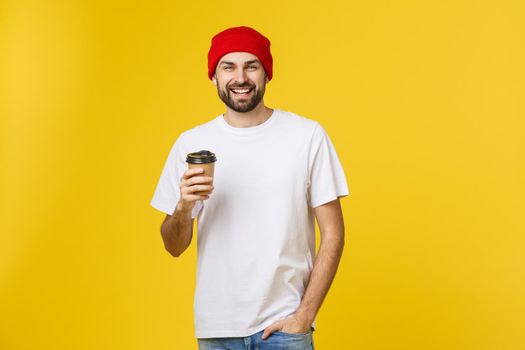 Man on isolated vibrant yellow color taking a coffee in takeaway paper cup and smiling because he will start the day well