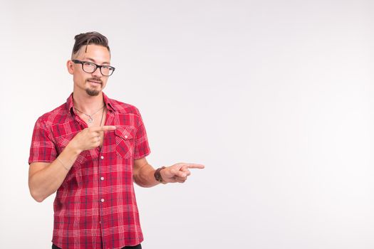 People, style and fashion concept - young handsome man in red shirt over white background pointing on copy space.