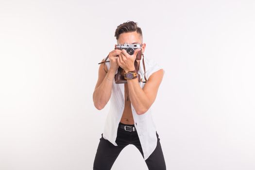 Technologies, photographing and people concept - handsome young man with retro camera over white background.