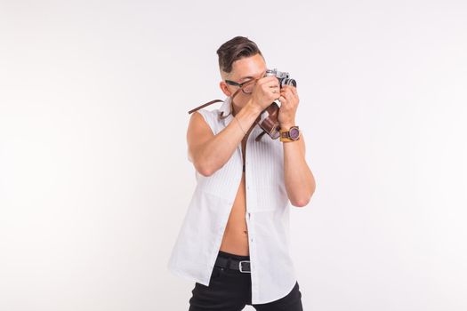 Technologies, photographing and people concept - handsome young man with retro camera over white background.