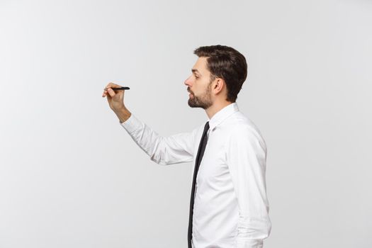 A view of a young businessman holding a pen, ready to write something, isolated on white background.