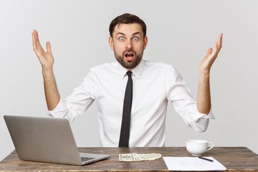 Young businessman in a workplace with surprise and shocked facial expression.