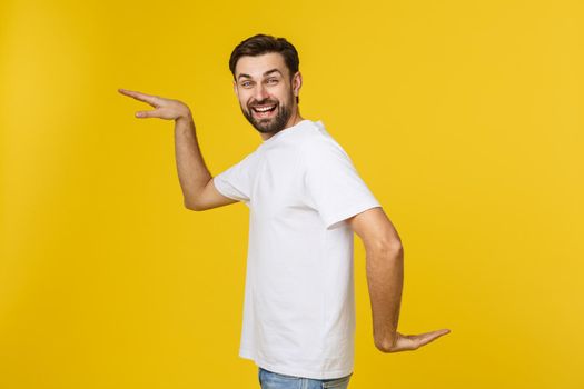 Young caucasian man isolated on yellow dancing and having fun