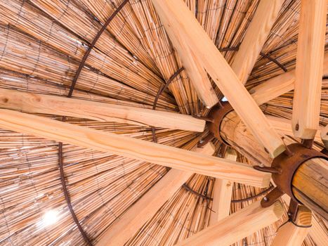 Straw beach umbrella from down side. Made of straw, wood and iron rings.