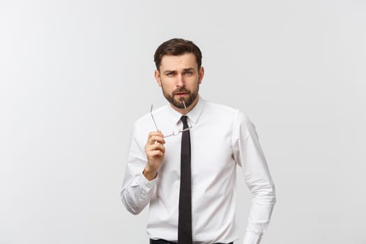 A handsome young Caucasian millennial man in glasses and a white T-shirt isolated on a gray studio background, looks at blank copy