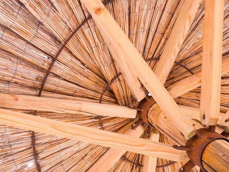 Straw beach umbrella from down side. Made of straw, wood and iron rings.