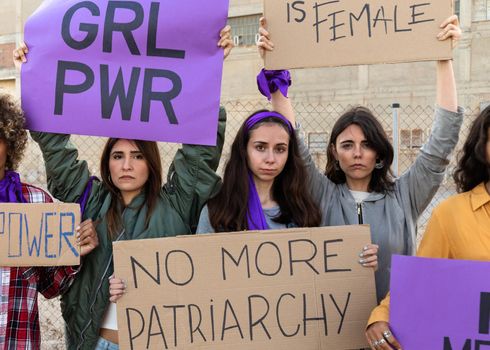 Multi-ethnic female protesters looking at camera holding woman empowerment signs in demonstration for equality. Woman empowerment concept.