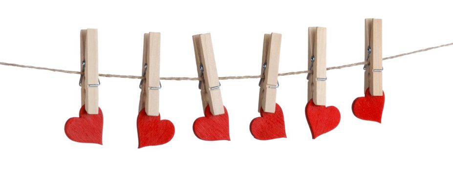 Clothes pegs and red wooden hearts on rope isolated on white background