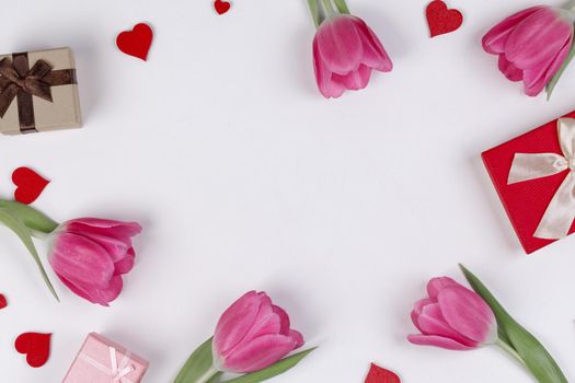 Flat lay valentines day frame with pink tulips hearts and gift boxes on a white background