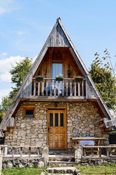 Two-storey triangular house with a terrace, a table and a bench at the entrance. Montenegro. High quality photo