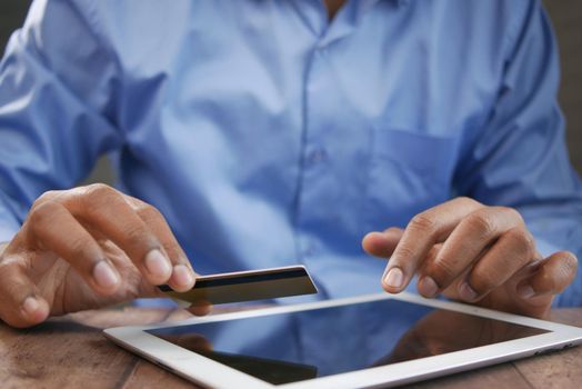 young man putting credit card detail on digital tablet ,