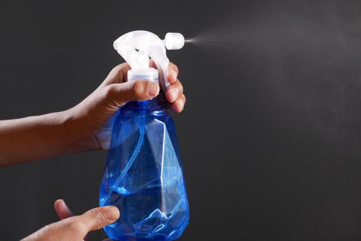 hand in blue rubber gloves holding spray bottle with copy space, top view