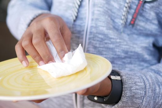 close up of young man wiping plate with a cloth .