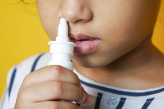 close up of sick child using nasal medicine spray.