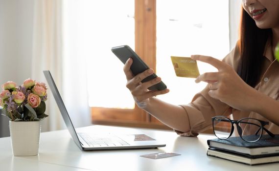 Happy woman using mobile app to online shopping and pay whit credit card at home.