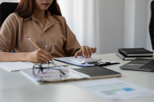 Business woman taking note to calculate business data, taxes, bills payment, Start up counting finance.accounting, statistics, and analytic research concept.