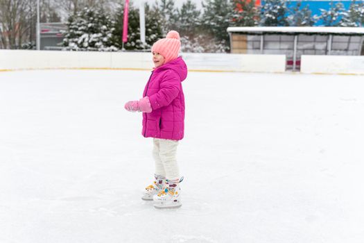 Adorable kid girl skating on ice rink