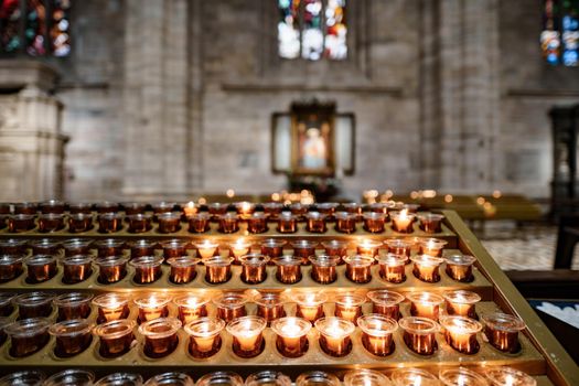 Votive candles are burning on a stand in the Duomo Cathedral. Close-up. High quality photo