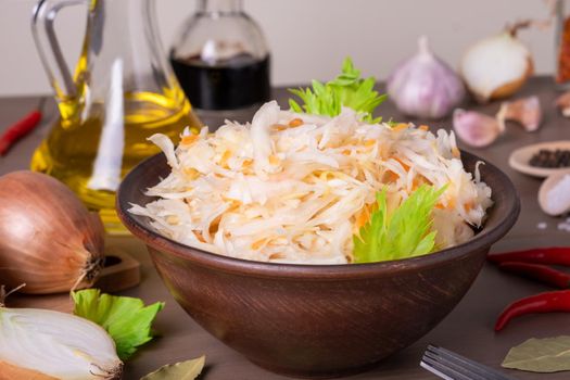 Close-up of sauerkraut fermented cabbage in ceramic sauerkraut bowl on table with spices and ingredients. Healthy healthy food. Russian kitchen. Selective focus.