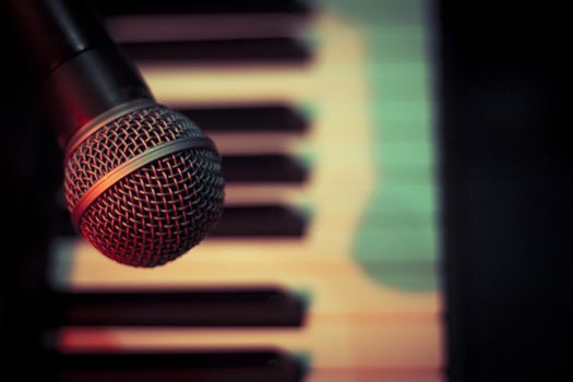 Microphone over piano keys in dim light. No people