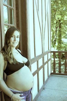 Seven months pregnant young woman dressed in black bikini and jeans
