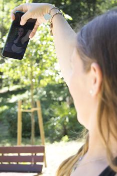 Seven month pregnant woman taking a selfie in a park