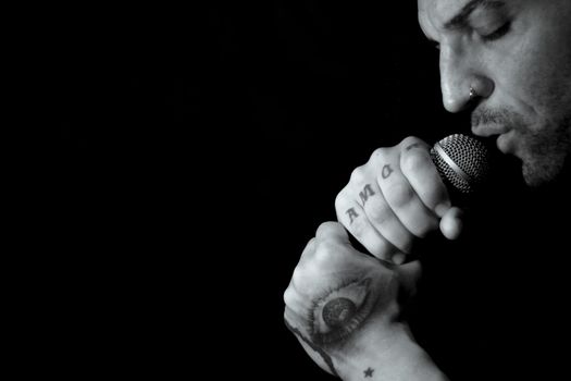 Singer man with round microphone on dark background. Copy space