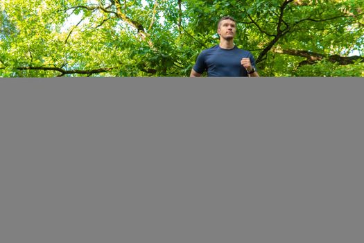 A man athlete runs in the park outdoors, around the forest, oak trees green grass young enduring athletic athlete healthy fitness outdoor athletic male, trees man. Autumn body spring, feet stretches