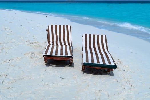 A close-up of sunbeds set on a beautiful tropical beach. Impressive image for every use.