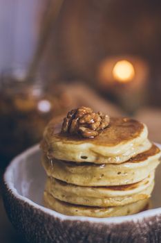 Stack of delicious pancakes with honey, nuts on wooden background.