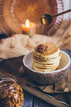 Stack of delicious pancakes with honey, nuts on wooden background.