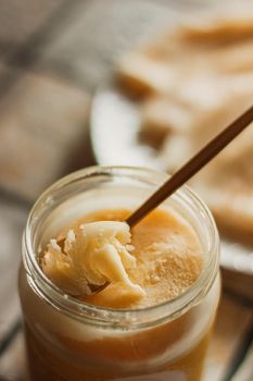 Ghee butter in glass jar and sliced bread on table. Healthy eating, breakfast.