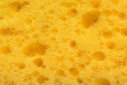 Foam sponge texture in macro. Textured background. Dishwashing or car cleaning concept. Abstract yellow wallpaper or backdrop for your design closeup